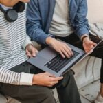 crop unrecognizable male men using laptop on street